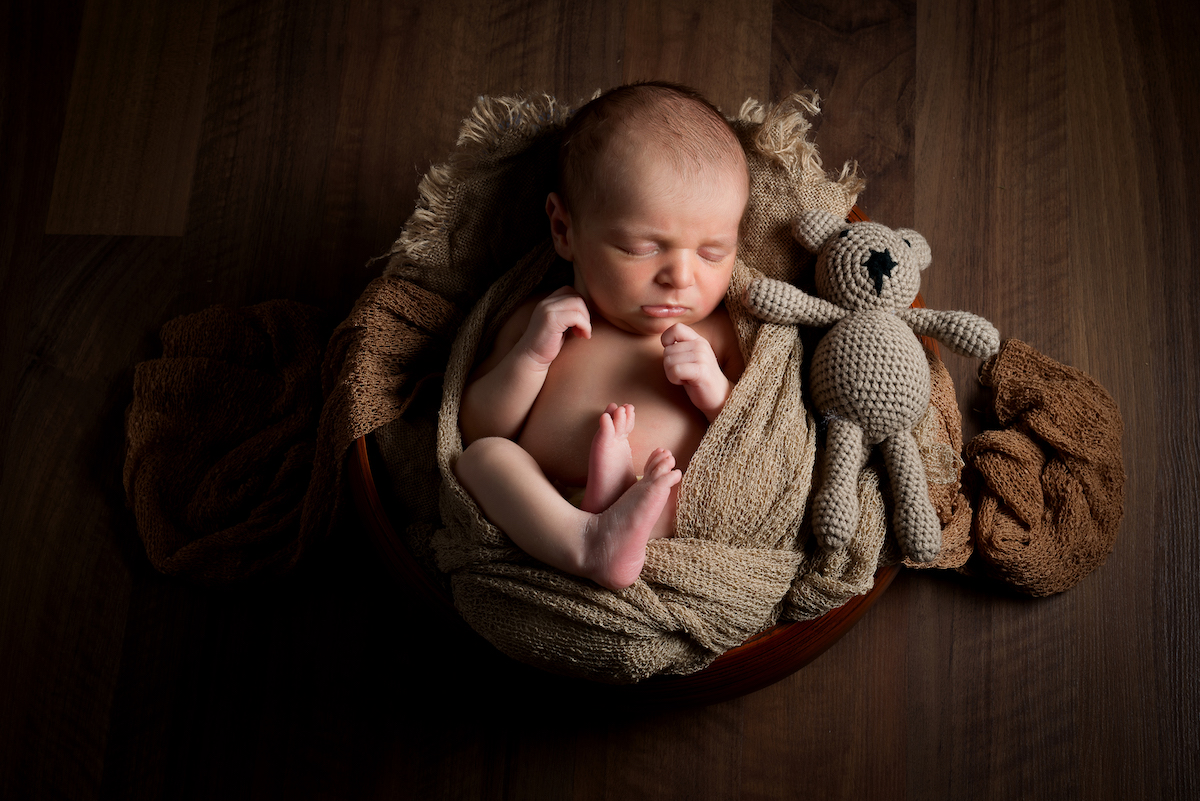 portrait d'un bébé allongée avec son doudou